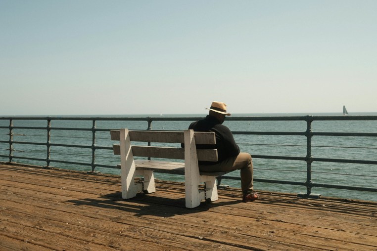 A man sat alone on a bench looking out at the sea
